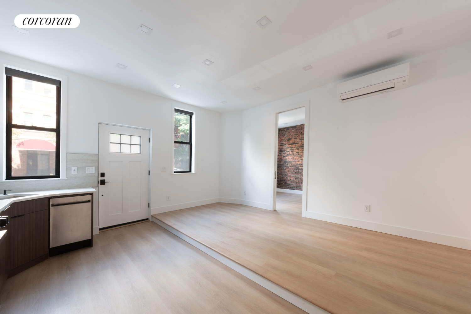 a view of an empty room with window and wooden floor