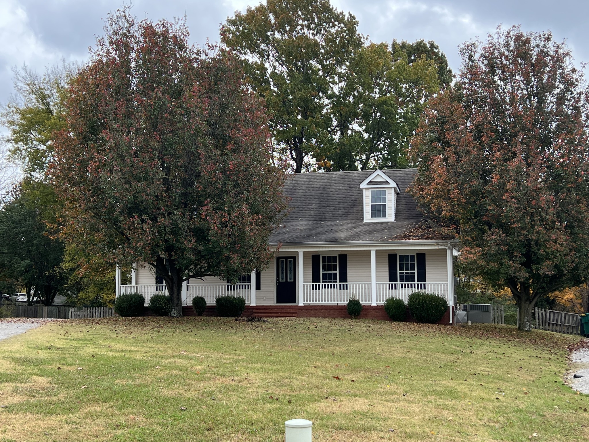 a front view of a house with a large tree