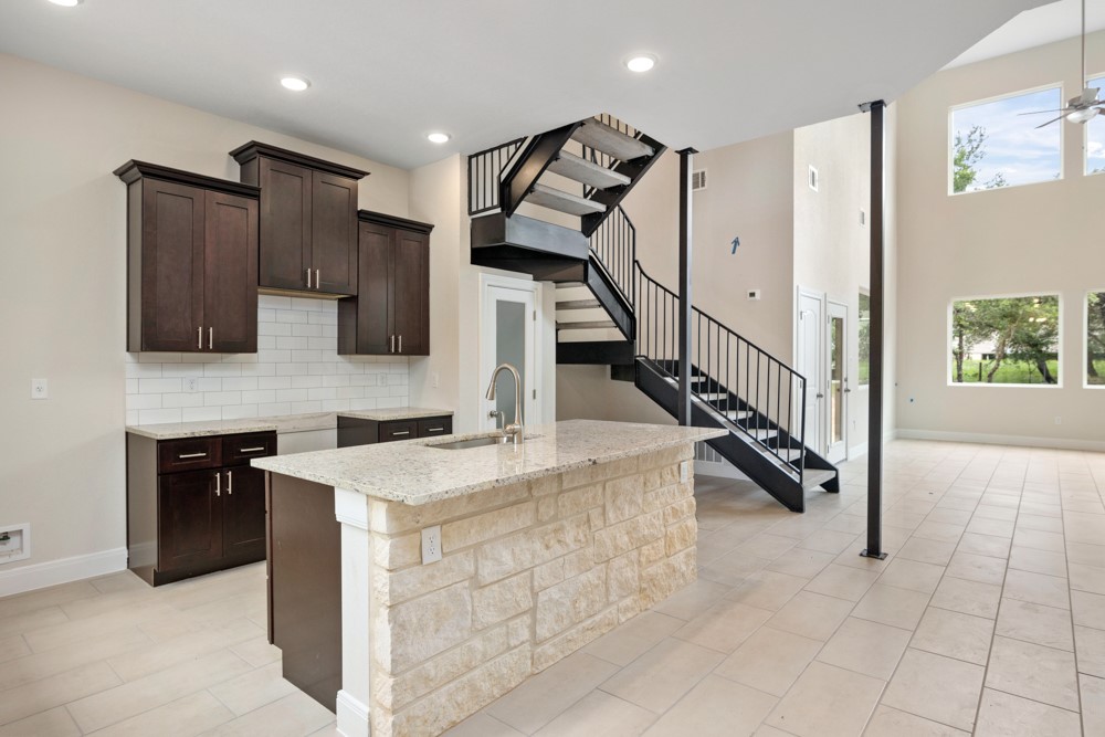 a kitchen with stainless steel appliances granite countertop a sink a stove top oven and a refrigerator