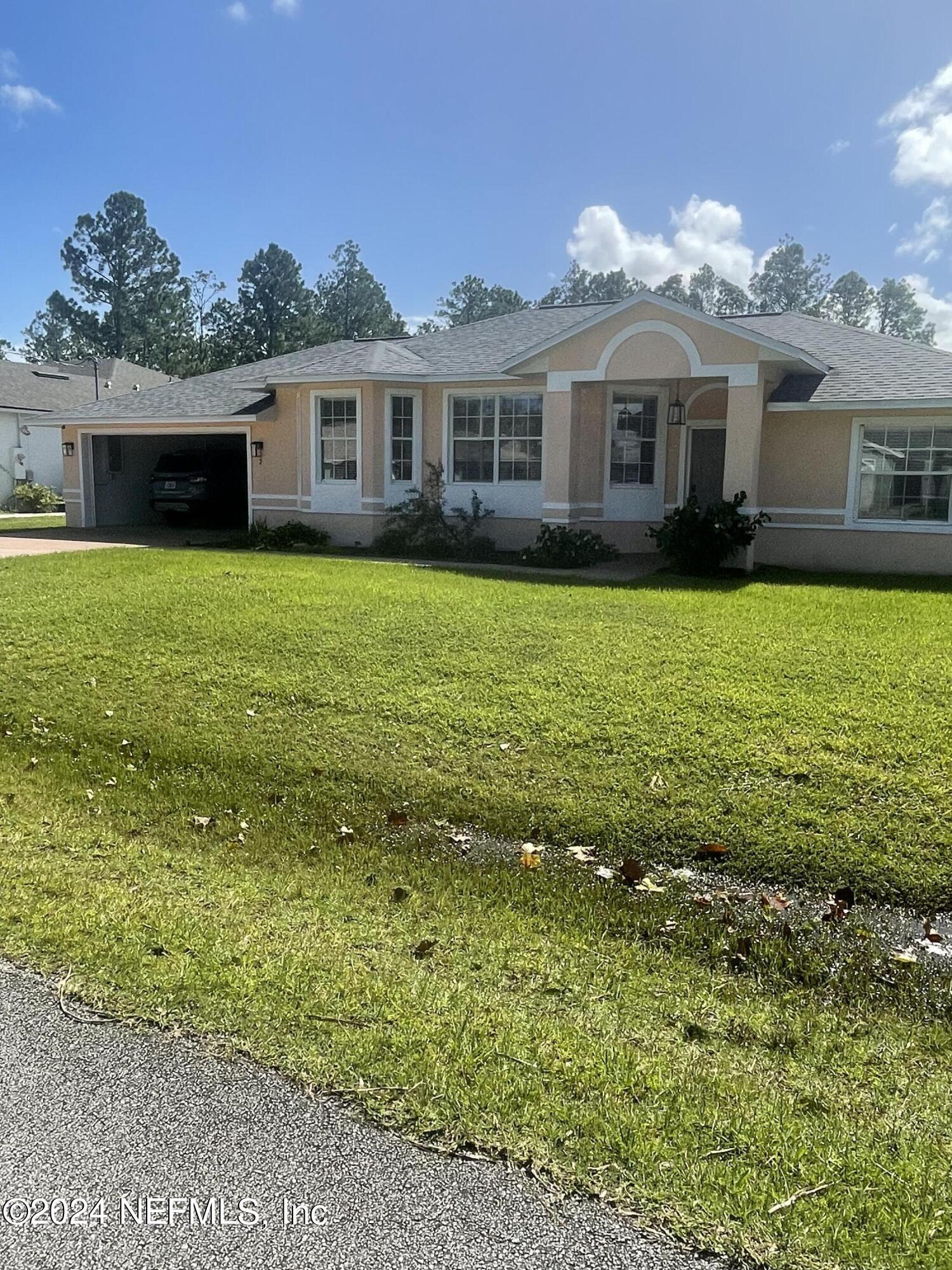 a front view of a house with a garden and lake view