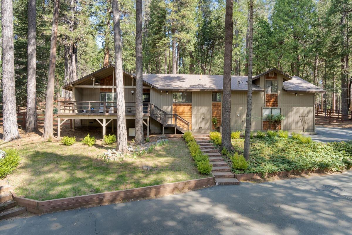 a view of a house with a small yard and large trees