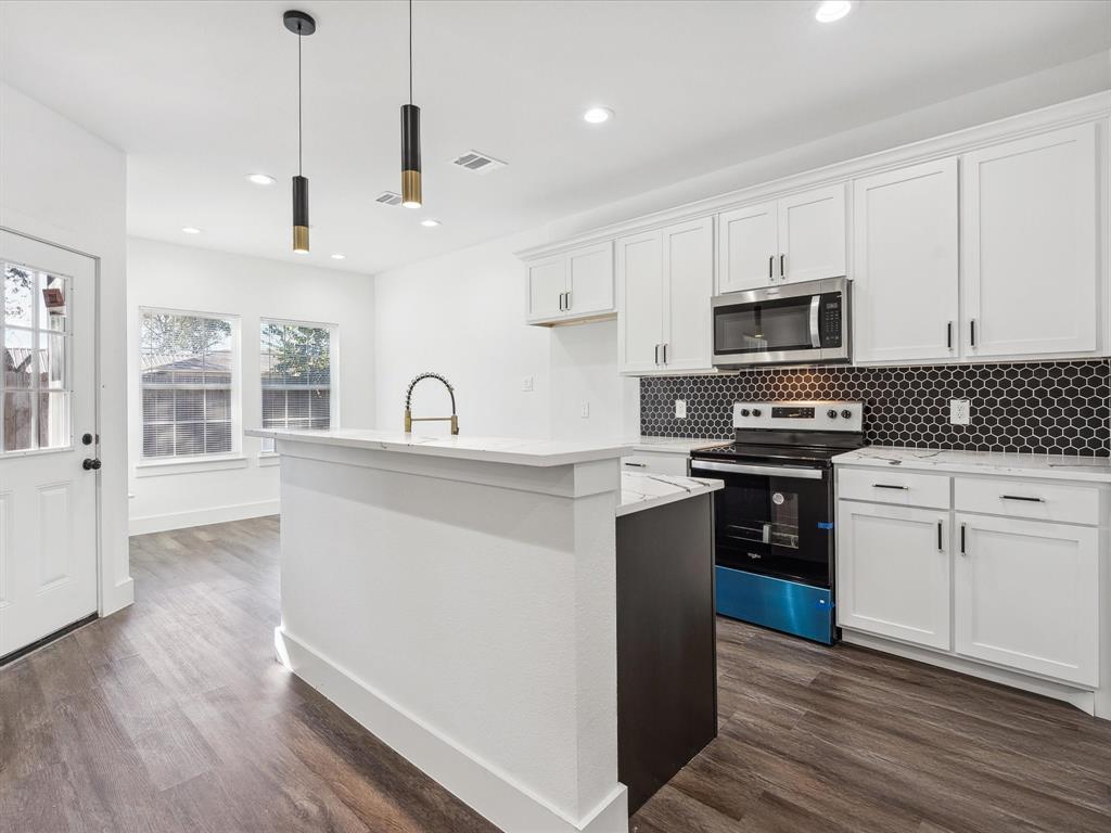 a kitchen with kitchen island granite countertop a sink cabinets and stainless steel appliances