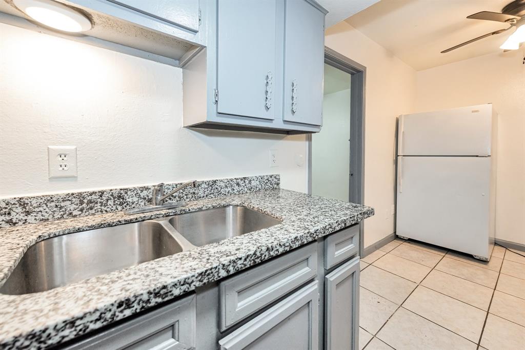 a kitchen with granite countertop a sink and a refrigerator