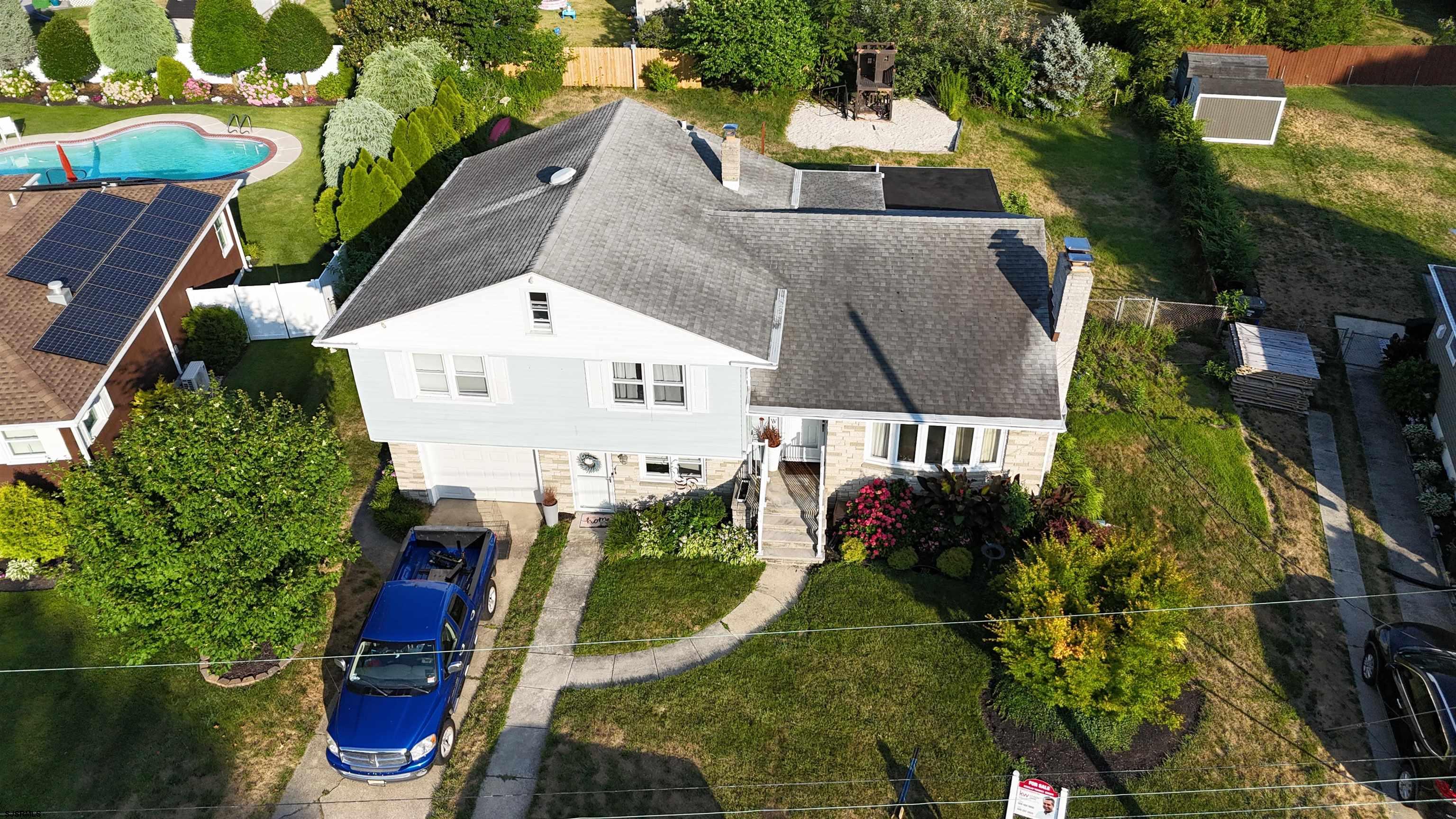 an aerial view of a house with swimming pool and large trees