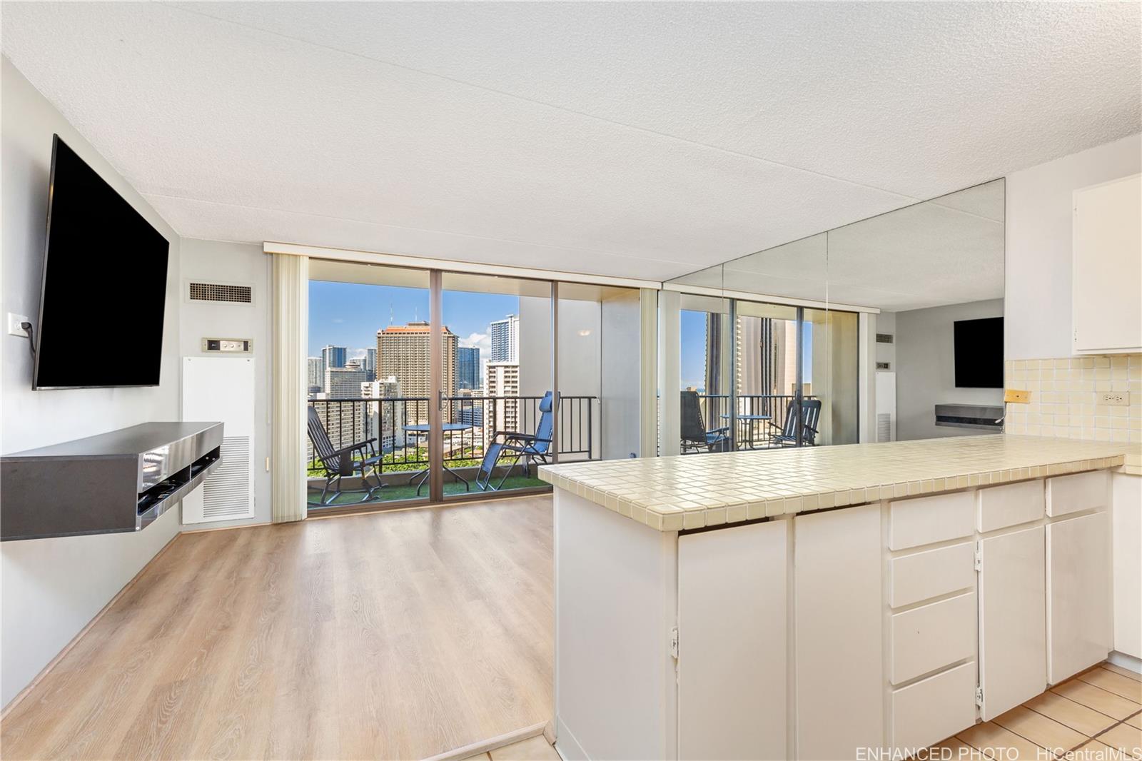 a living room with stainless steel appliances kitchen island granite countertop a sink and a flat screen tv