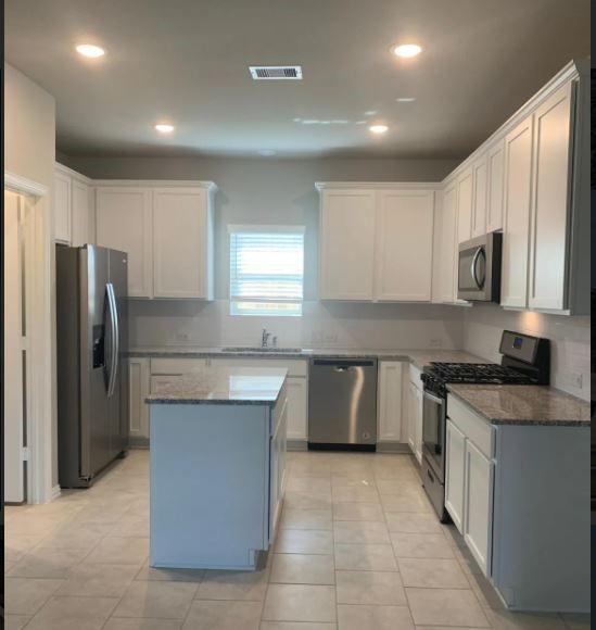 Island kitchen with stainless steel applicances (including the refrigerator) and plenty of meal prep space.