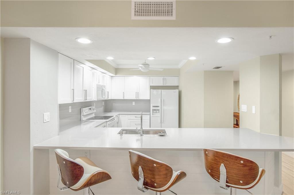 a kitchen with kitchen island granite countertop a sink and a stove top oven with wooden floor