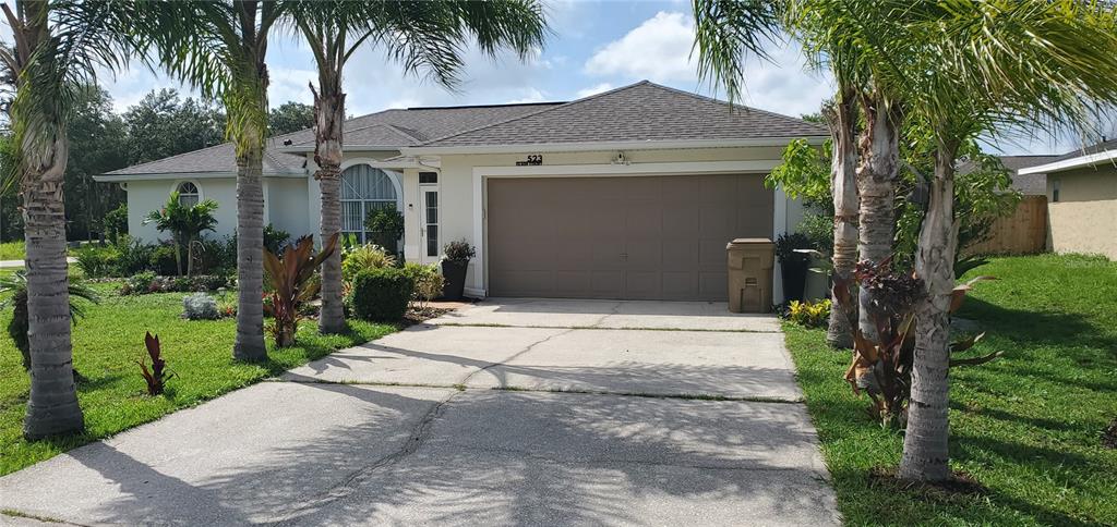 front view of house with a yard and palm trees