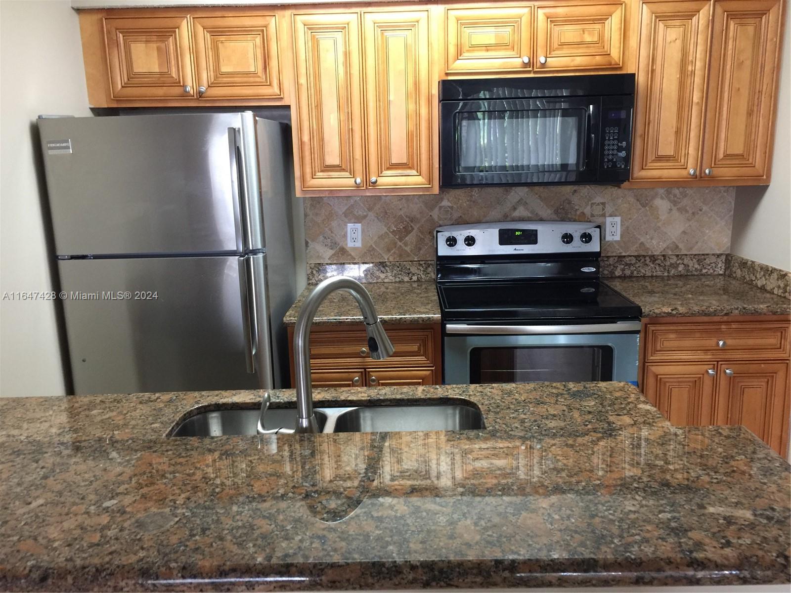 a kitchen with granite countertop a refrigerator stove and sink