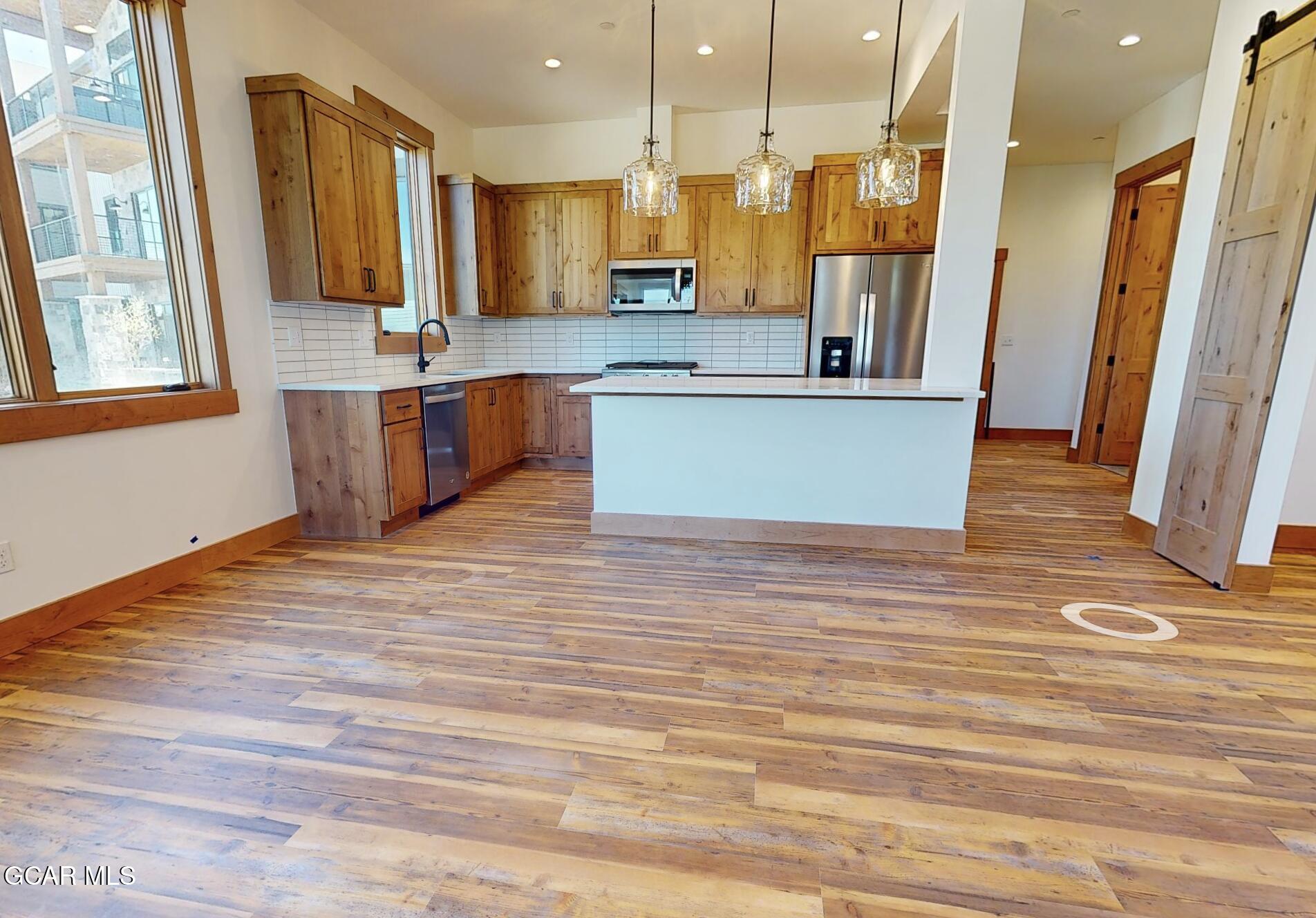 a view of kitchen with stainless steel appliances granite countertop a stove a sink and a refrigerator