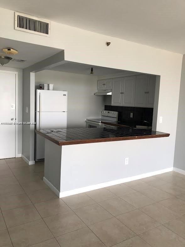 a kitchen with stainless steel appliances a refrigerator a sink and white cabinets