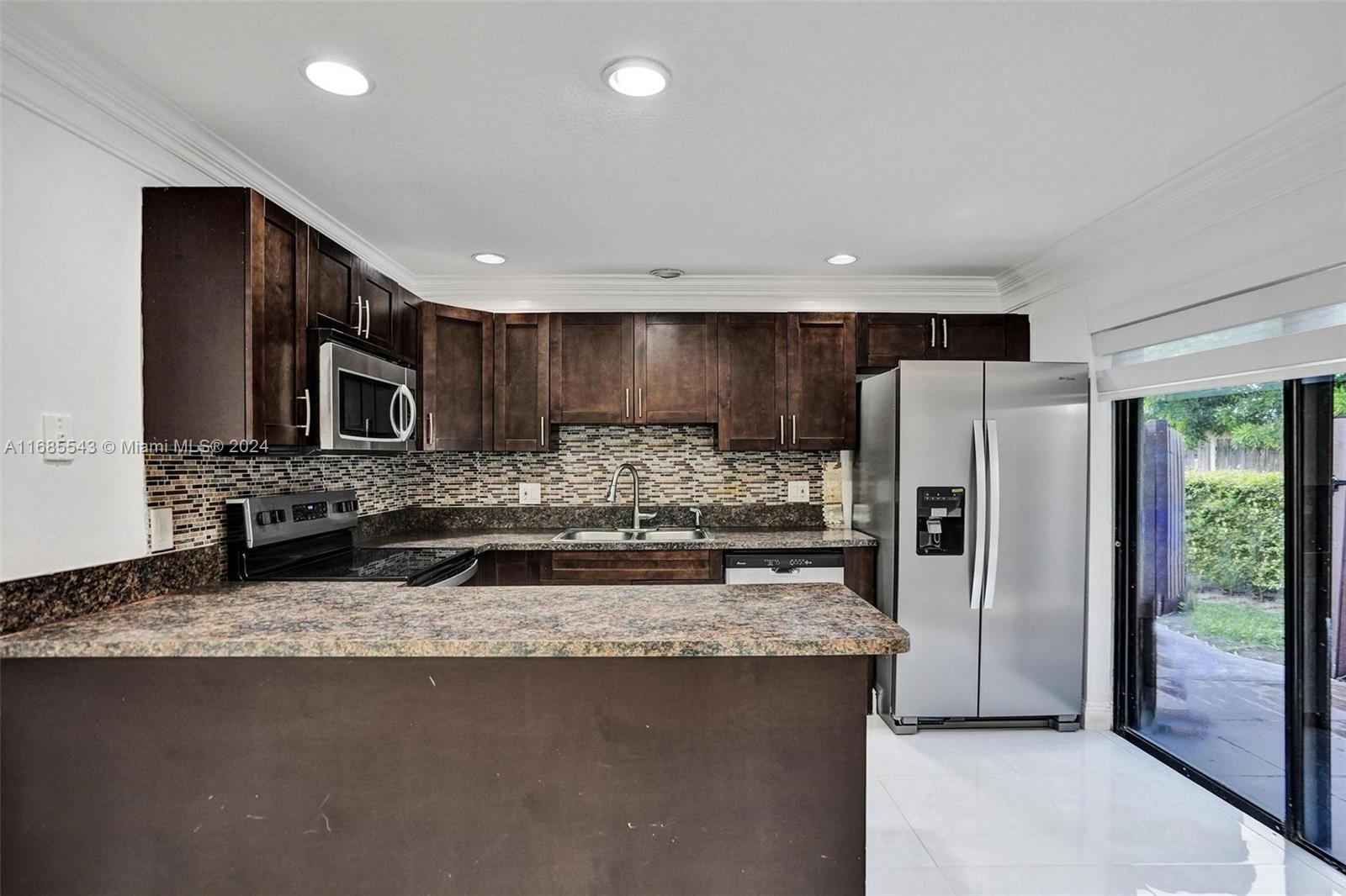 a kitchen with stainless steel appliances granite countertop a sink and a refrigerator