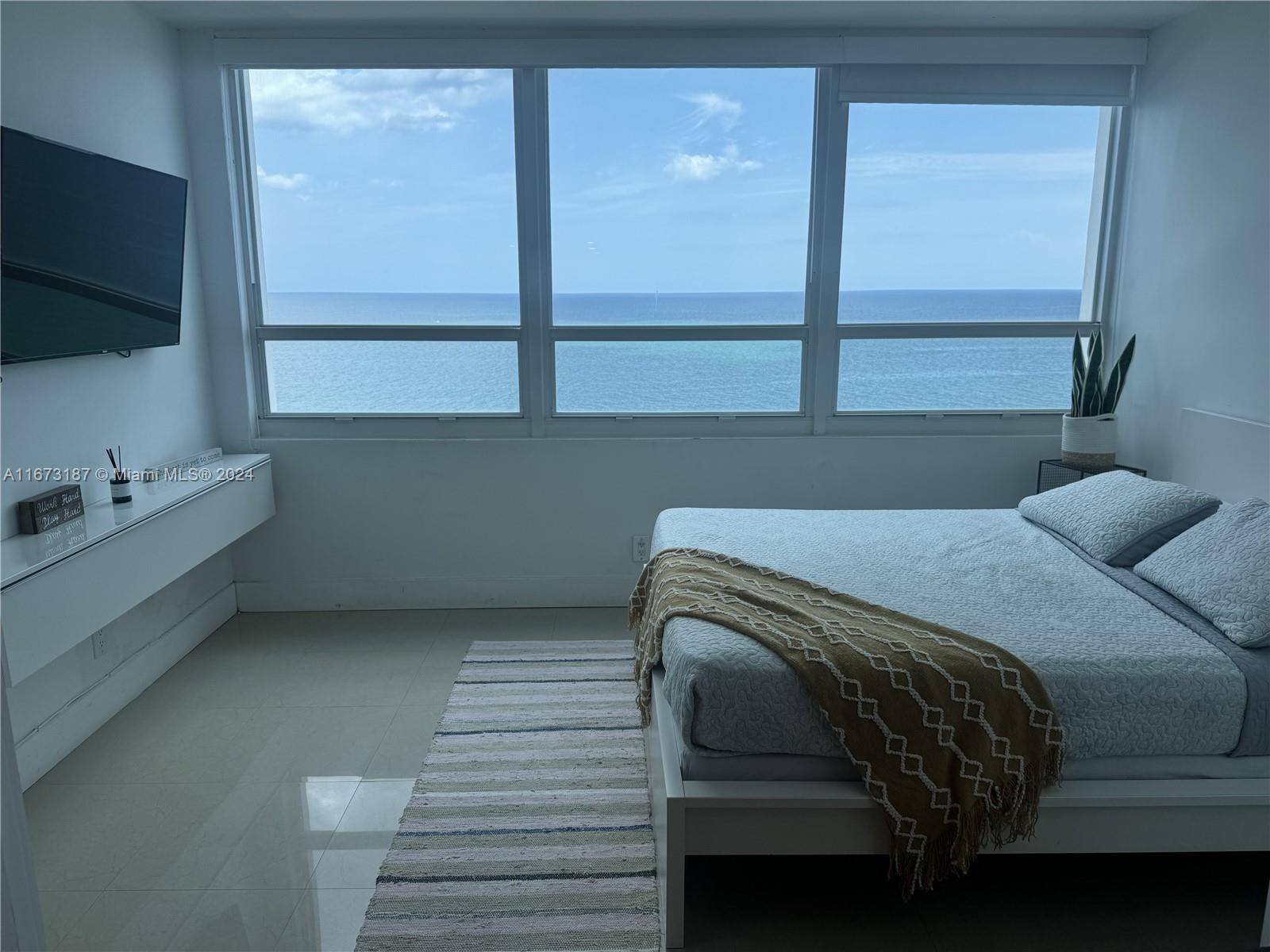 a bedroom with a bed and a flat tv screen on the dresser