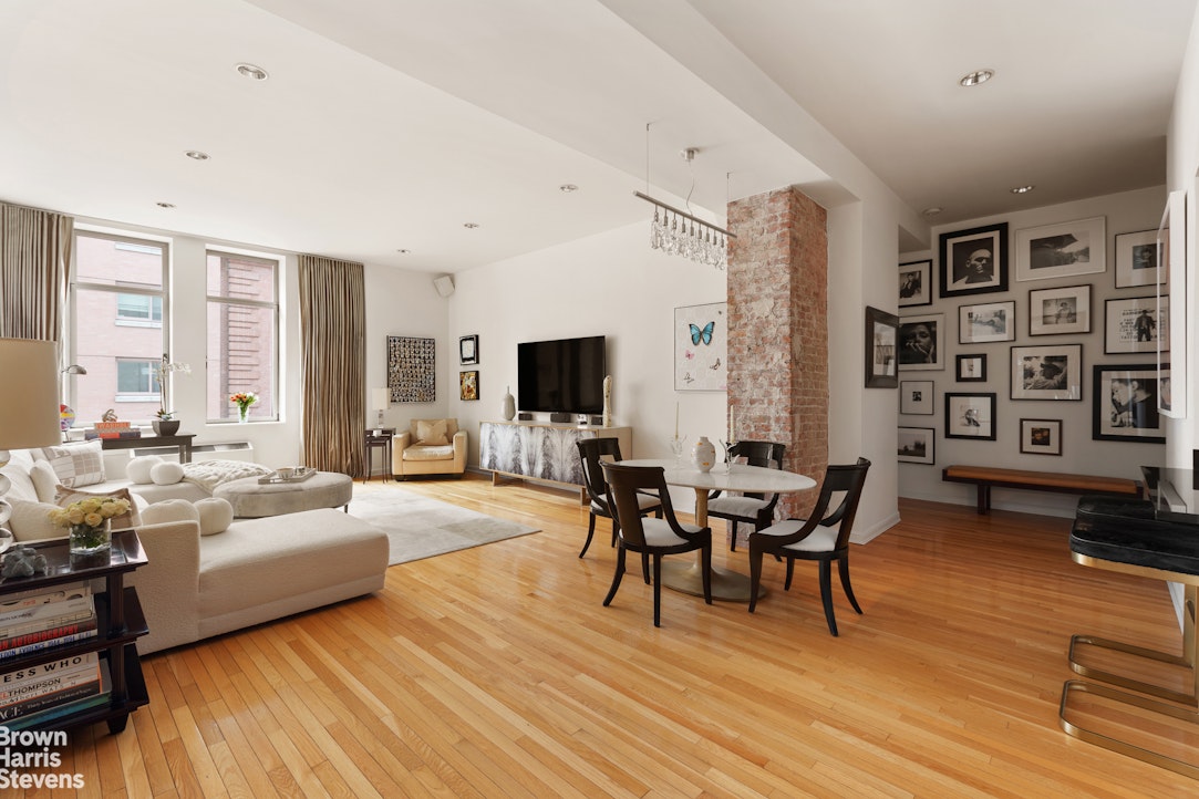 a living room with furniture wooden floor and floor to ceiling windows