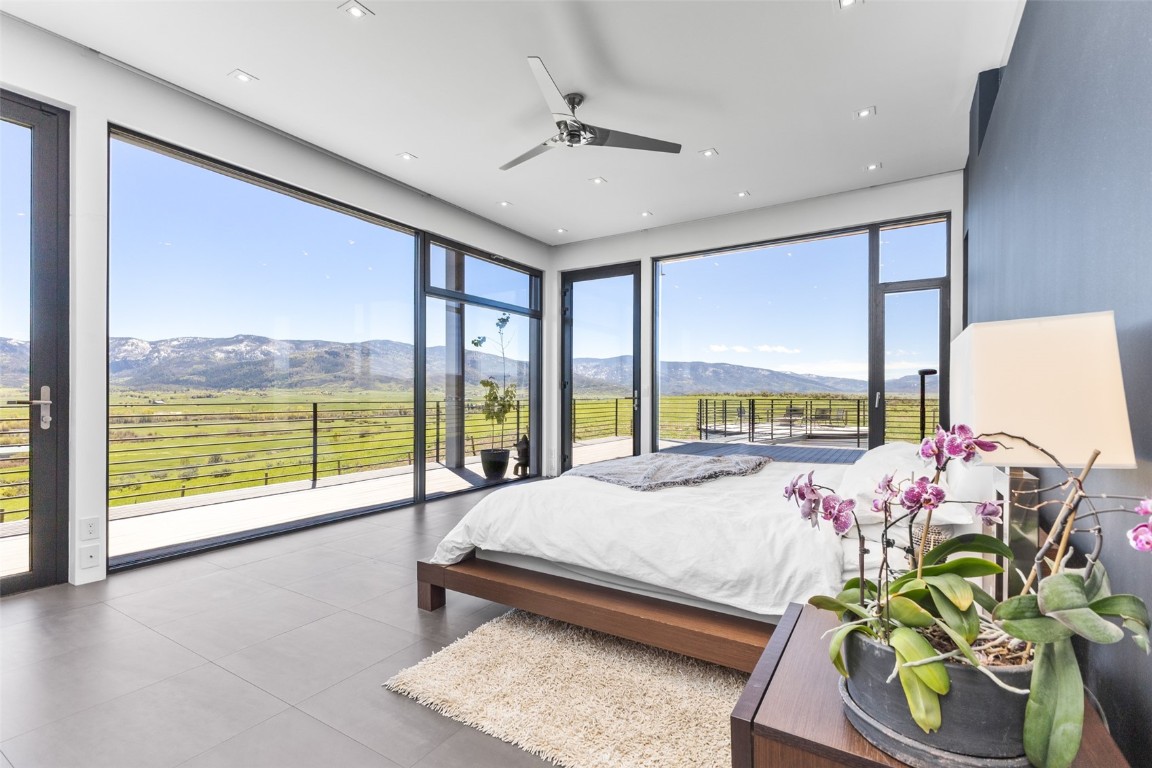 Tiled bedroom with ceiling fan, a mountain view, and access to outside