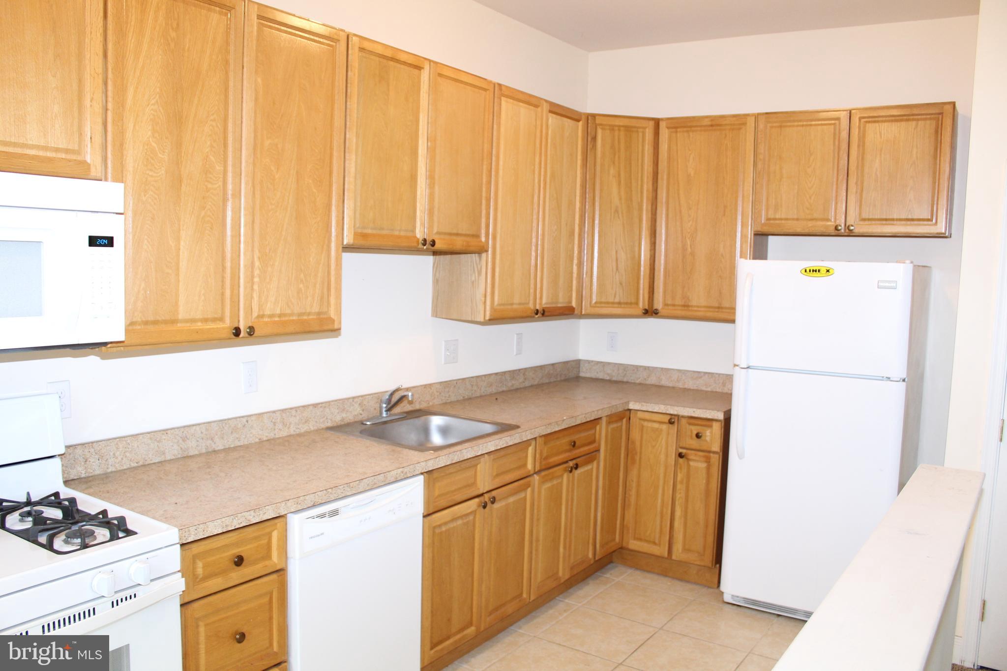 a utility room with a sink a cabinetry and a refrigerator