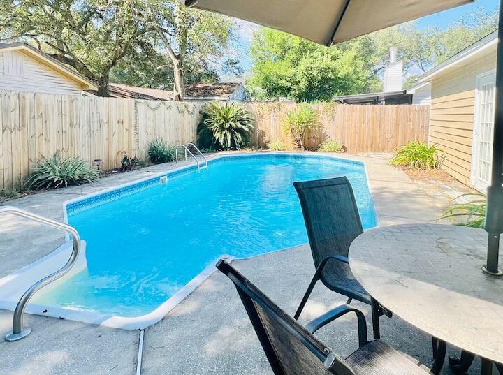 a view of a chairs and table in patio with swimming pool