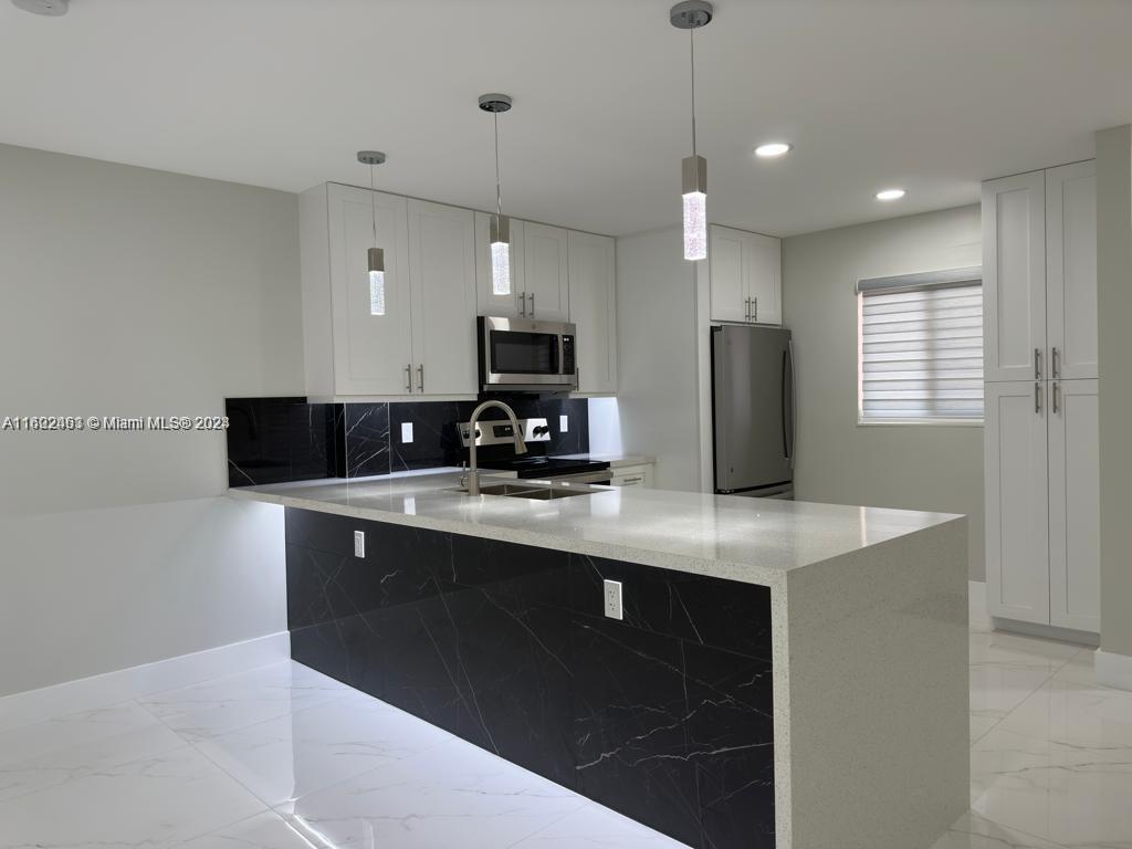 a kitchen with stainless steel appliances granite countertop a sink a stove a refrigerator a center island and cabinets