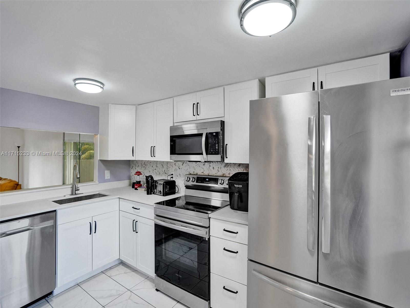 a kitchen with white cabinets stainless steel appliances and sink