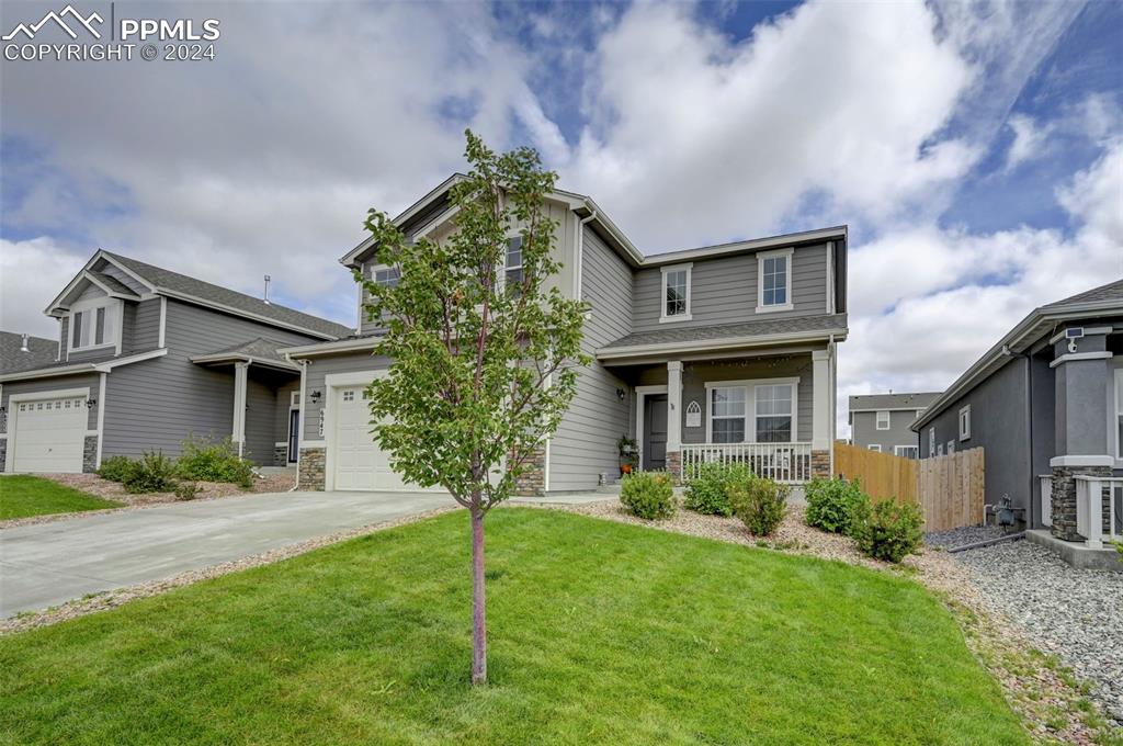 Craftsman house with a garage, a front yard, covered porch, and central AC