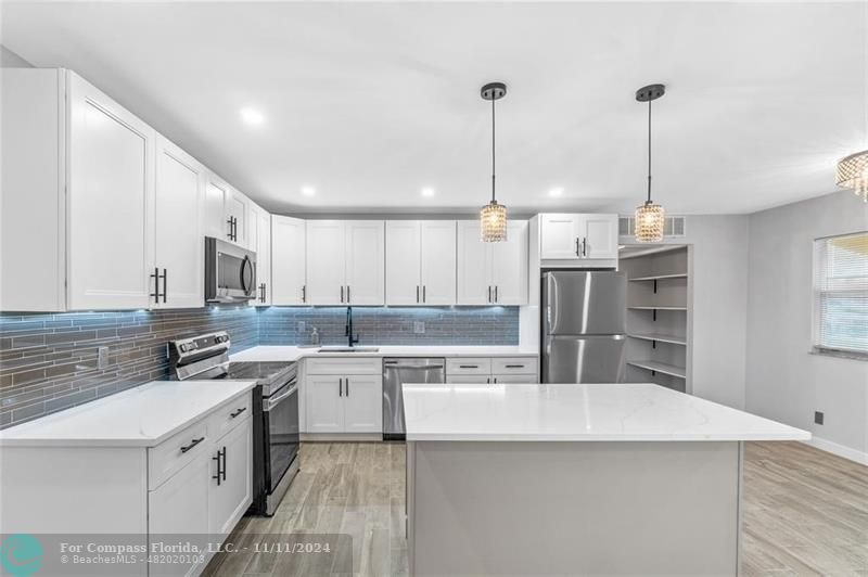 a kitchen with a sink a counter top space stainless steel appliances and cabinets