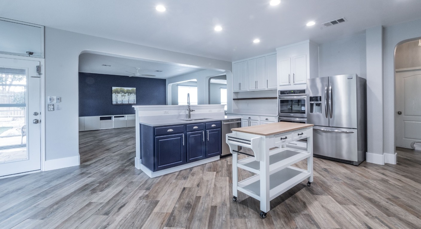 a kitchen with stainless steel appliances kitchen island granite countertop a stove refrigerator and cabinets