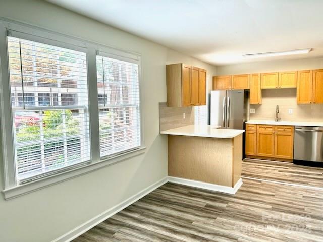 a view of a kitchen with kitchen island wooden floor and stainless steel appliances