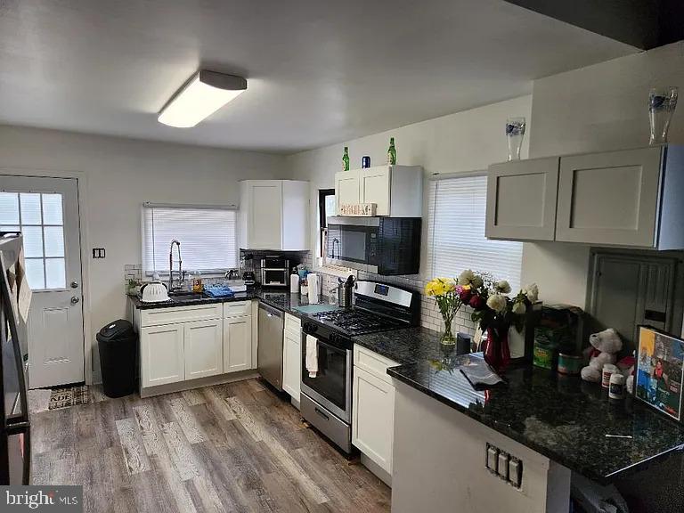 a kitchen with stainless steel appliances granite countertop a sink stove refrigerator and cabinets