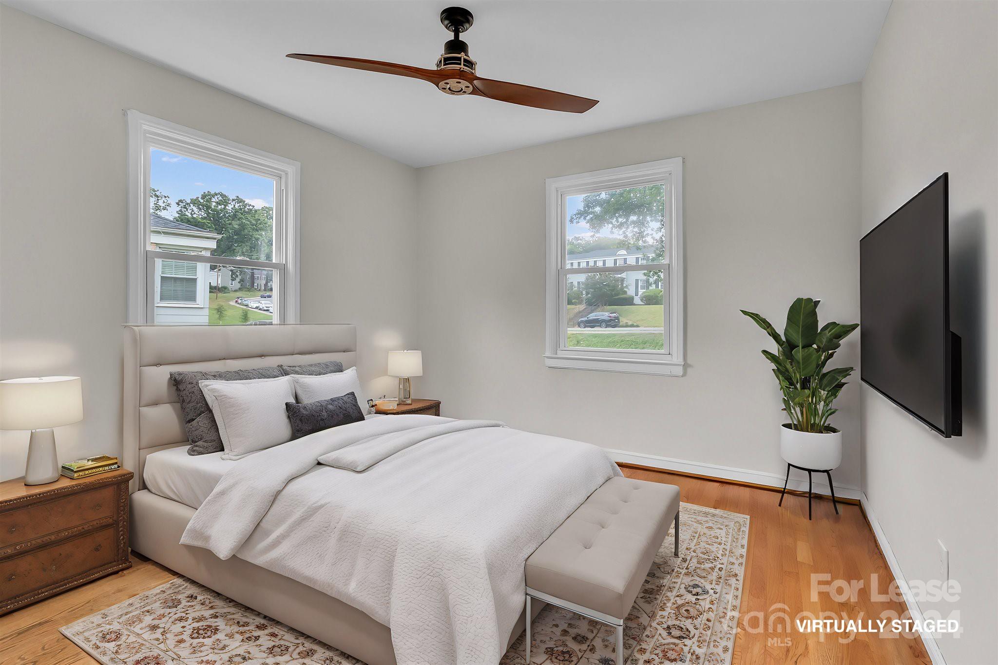 a bedroom with a bed and a potted plant on the dresser