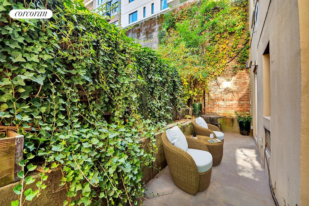 a view of a garden with lawn chairs and potted plants