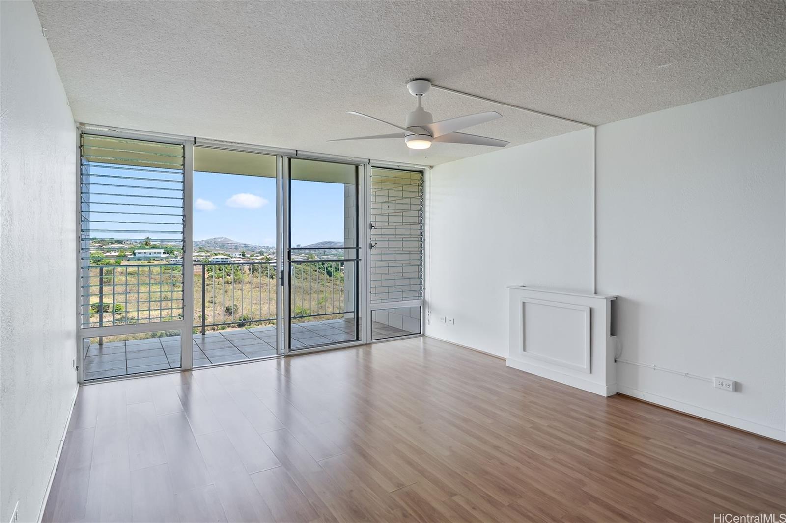 a view of empty room with wooden floor and fan