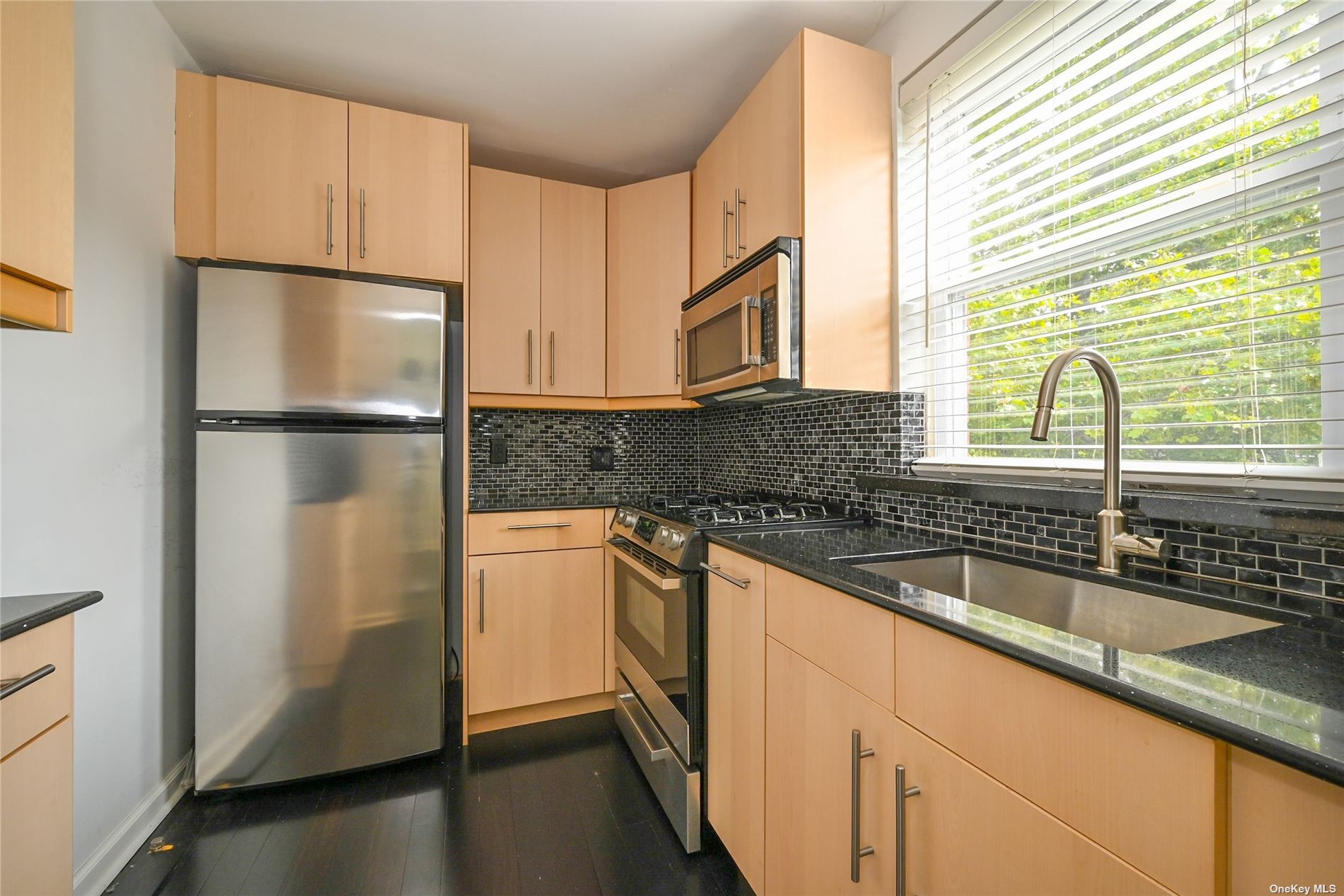 a kitchen with granite countertop stainless steel appliances a refrigerator sink and microwave