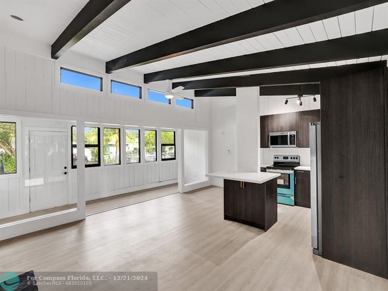 a living room with stainless steel appliances kitchen island granite countertop a refrigerator and a sink