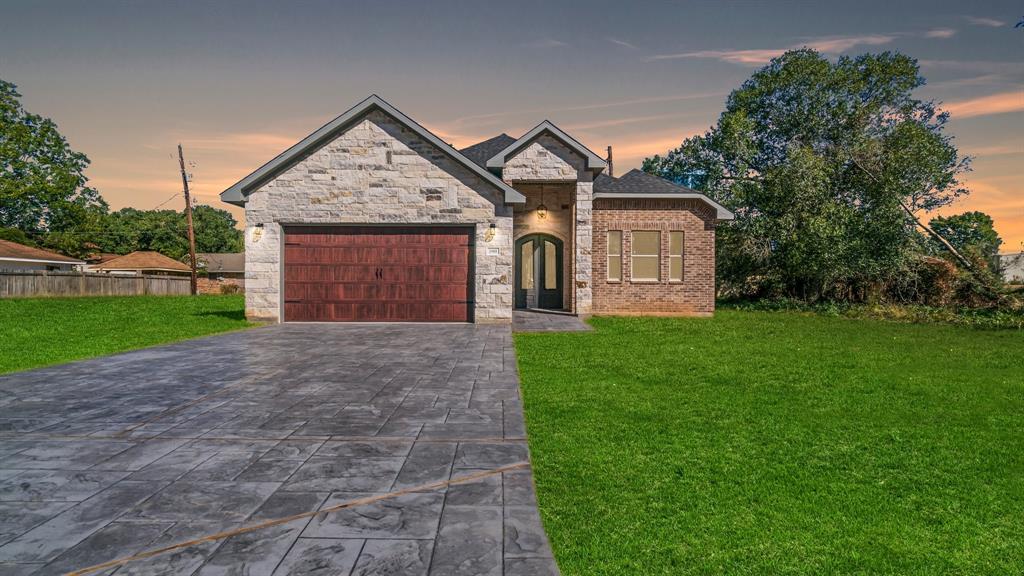 This is a single-story home featuring a blend of brick and stone facade with an attached two-car garage. Pavers for a drive way gives a custom home look.