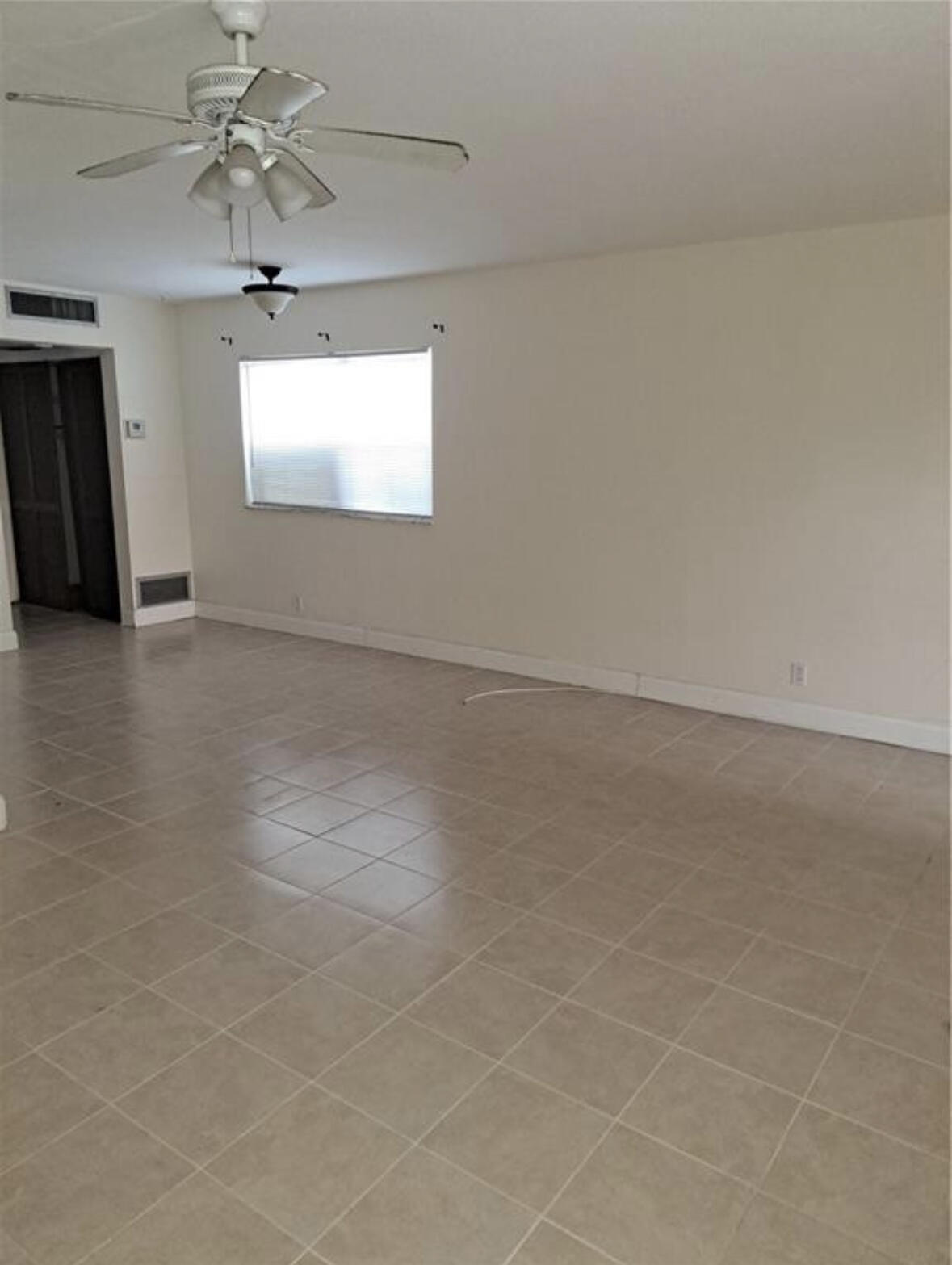 an empty room with chandelier fan and windows