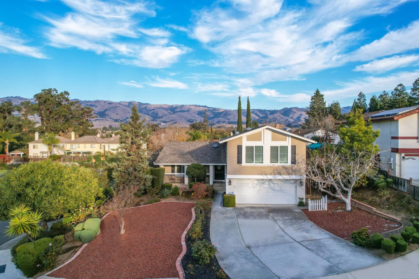 a front view of a house with a yard and mountain view in back