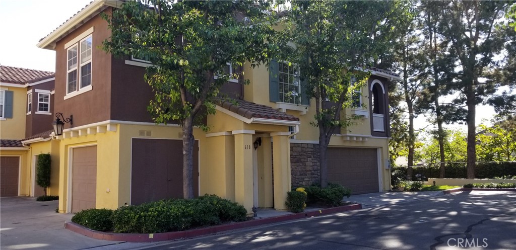 a view of a house with brick walls plants and large tree