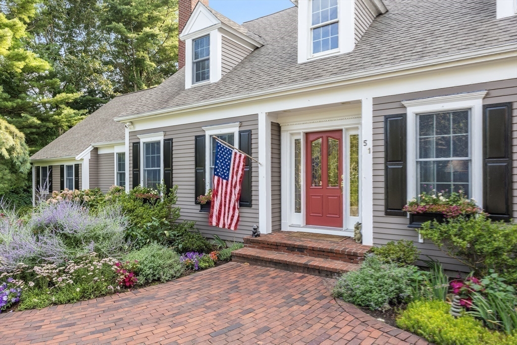 front view of a house with potted plants and a bench