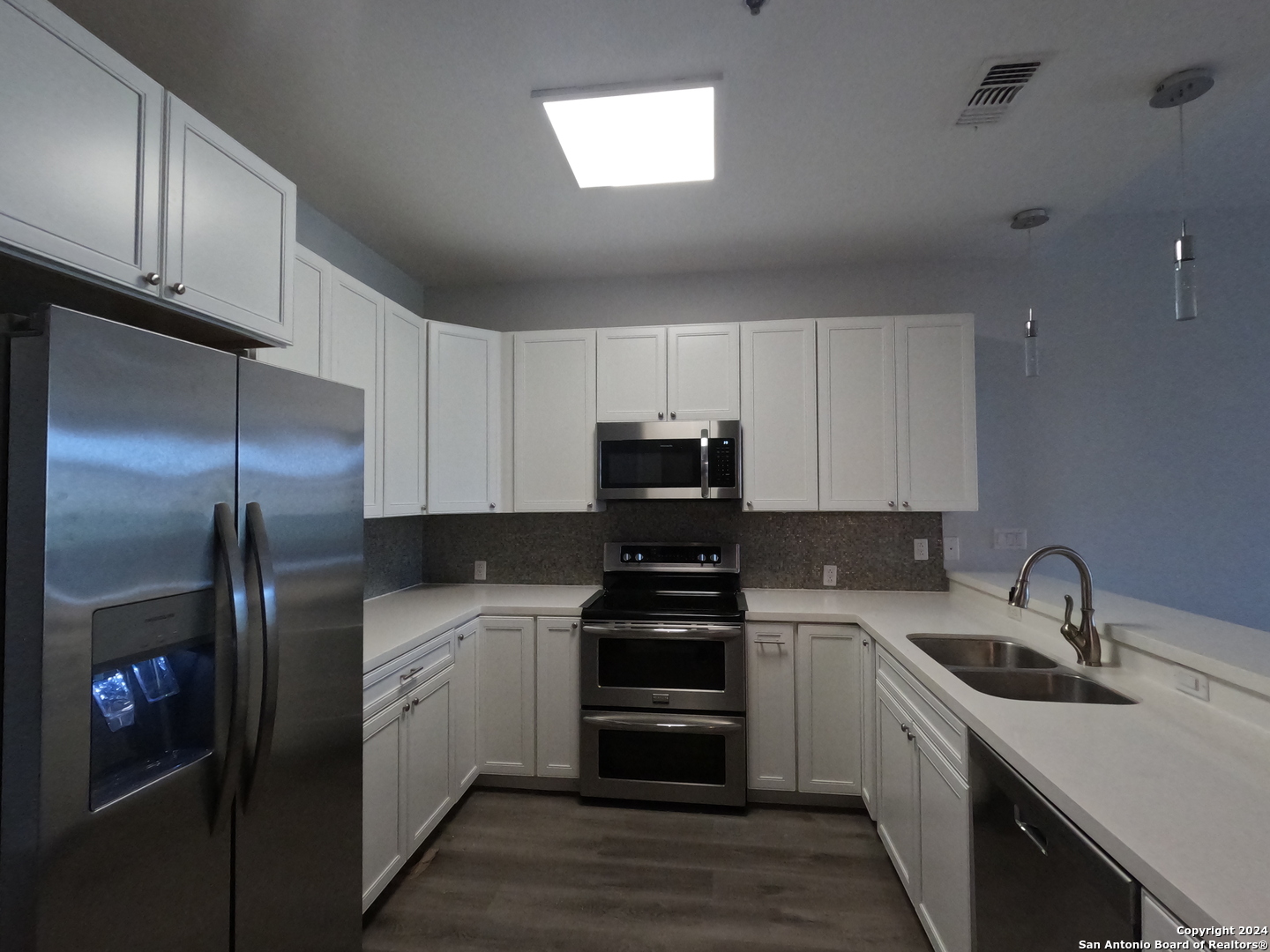 a kitchen with a sink a refrigerator a stove and cabinets