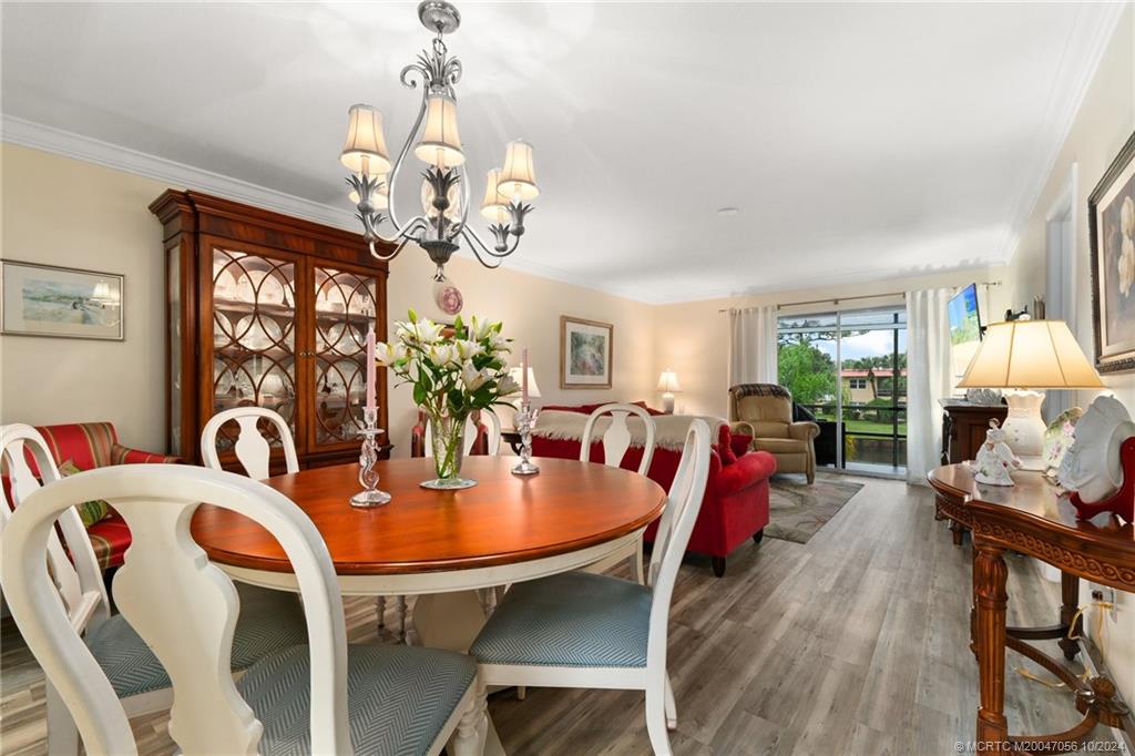 a dining room with wooden floor a chandelier a wooden table and chairs