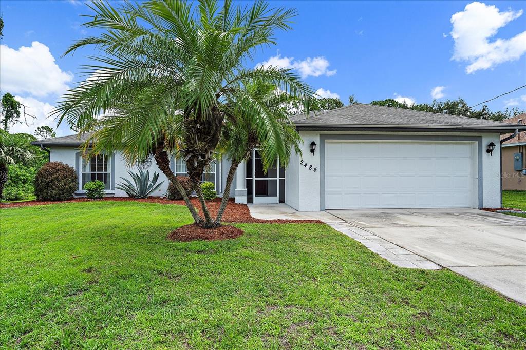 a front view of a house with a yard and palm trees