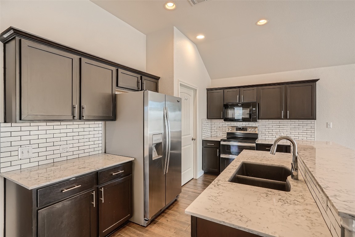 a kitchen with stainless steel appliances a stove a sink a refrigerator and a cabinets