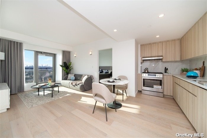 a living room with furniture a large window and stainless steel appliances