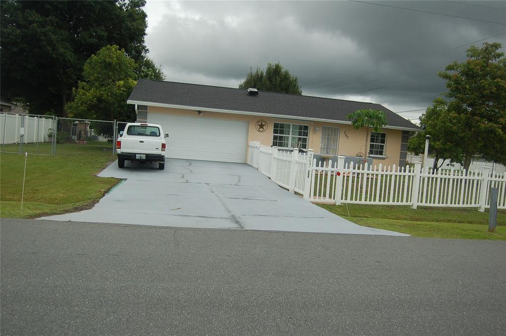 a view of a house with a small yard and large trees