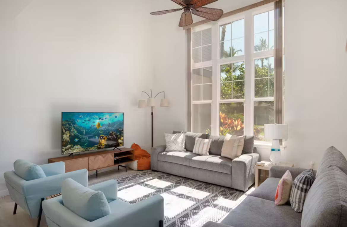 a living room with furniture a flat screen tv and a large window