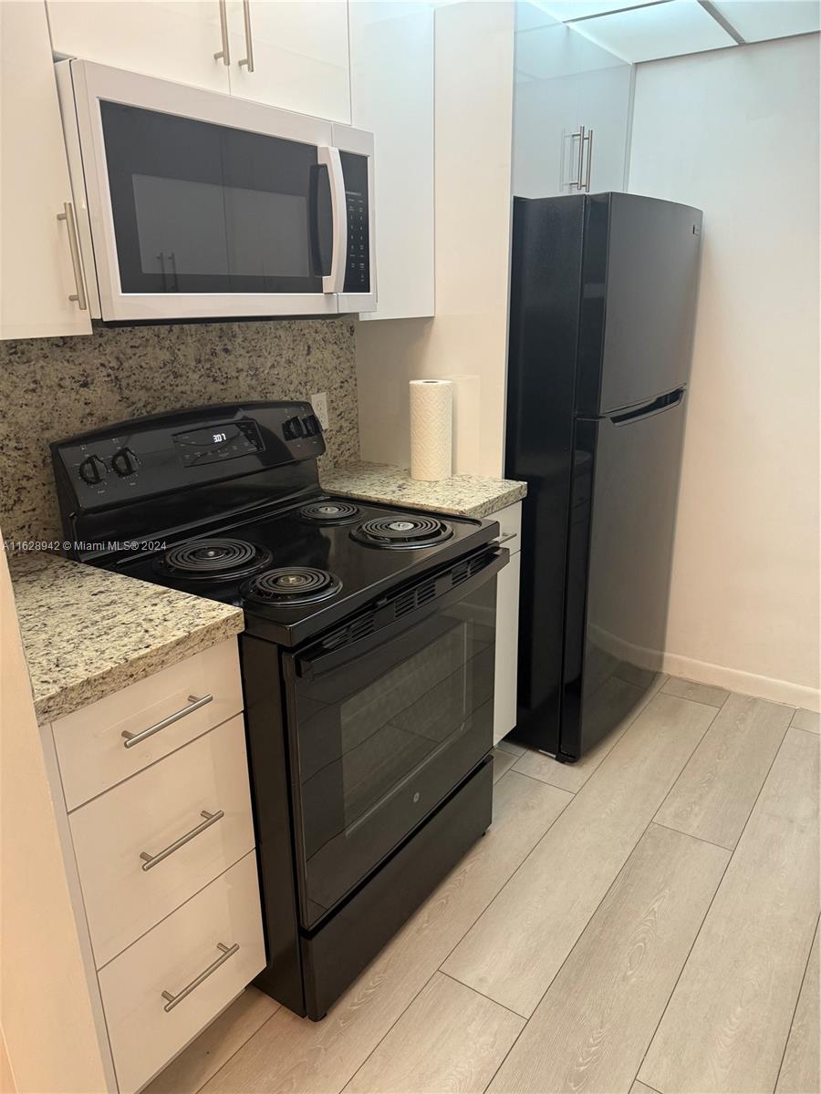 a kitchen with granite countertop white cabinets and stainless steel appliances