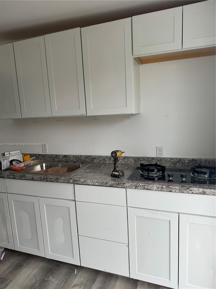 a kitchen with granite countertop white cabinets and sink