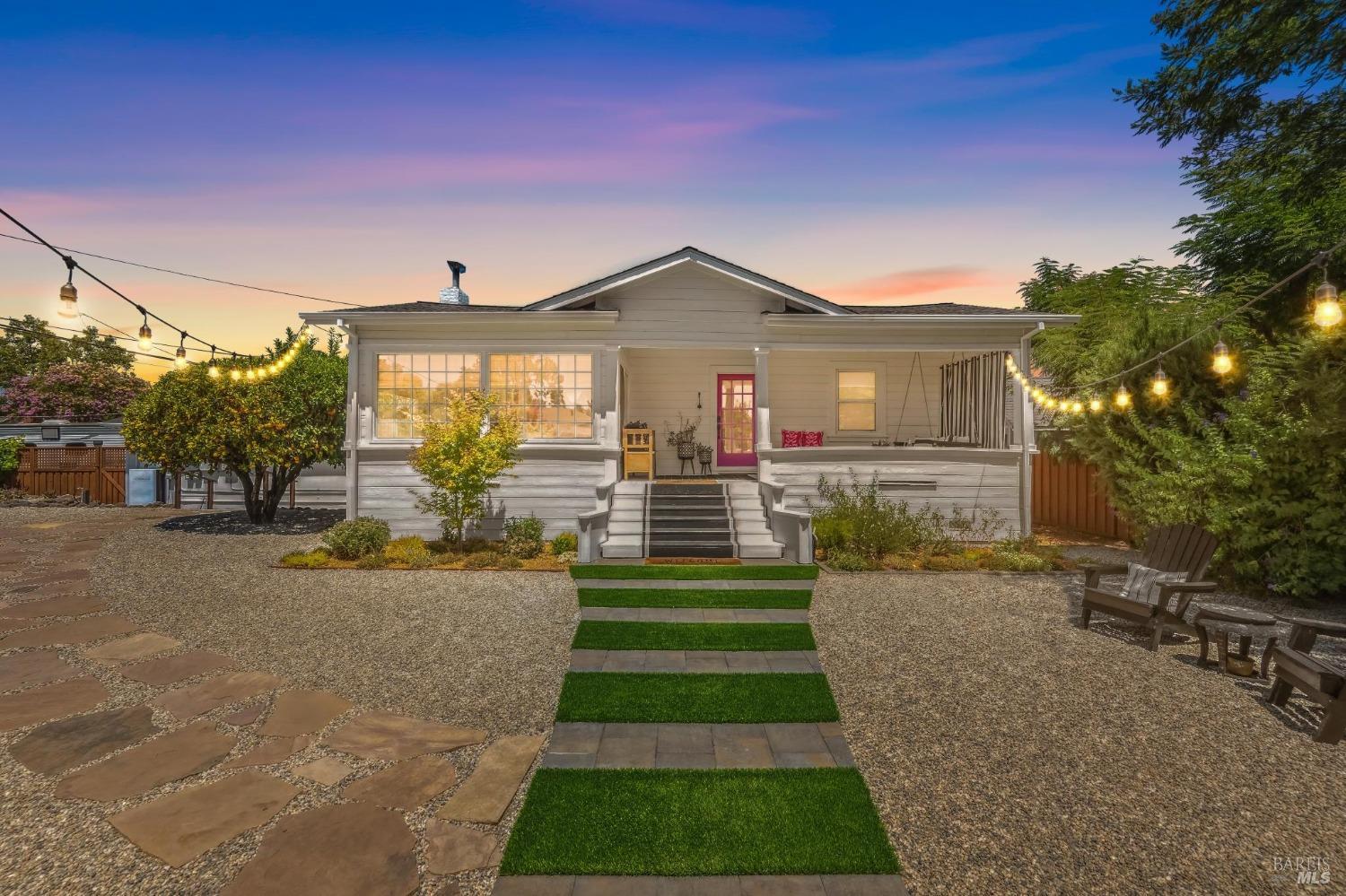 a front view of a house with a yard and potted plants