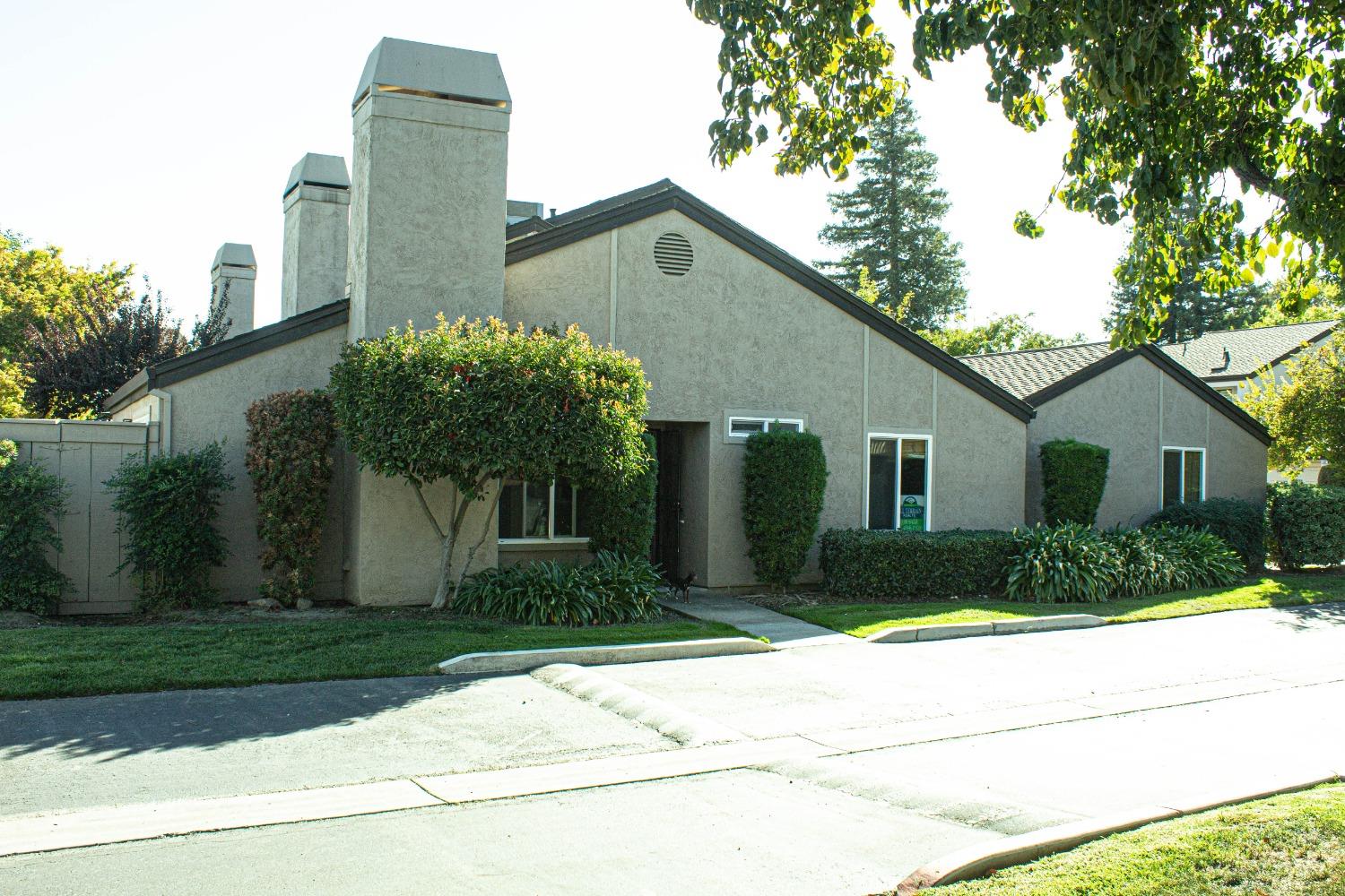 a front view of a house with a yard and potted plants