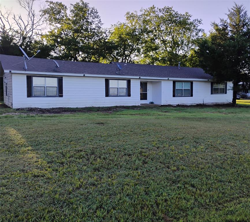 a house is sitting in middle of the green field